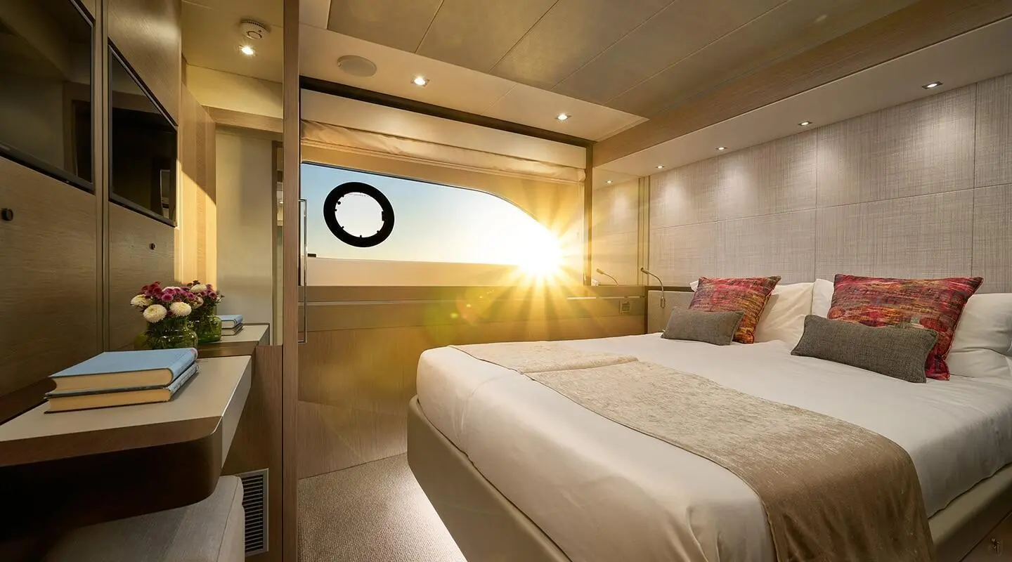Two twin beds in a yacht cabin with porthole and warm lighting