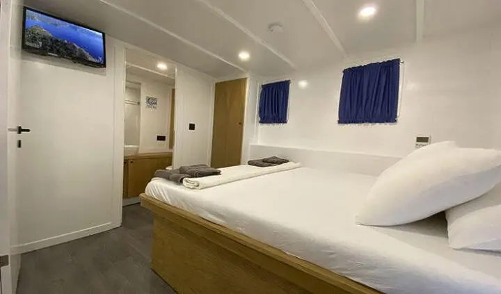 Maske 5 master cabin with king bed and ensuite bathroom, bright with blue drapes