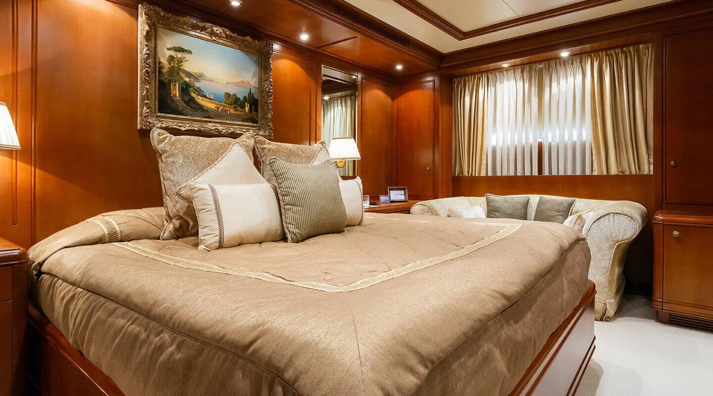 Luxurious yacht Apogee bedroom with large bed, wood-panel walls, and soft lighting
