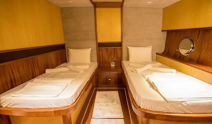 Nevra Queen yacht cabin with two wooden berths and white bedding