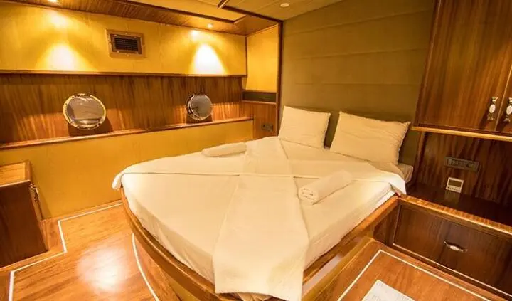 Nevra Queen yacht cabin with two single beds arranged together and overhead lighting