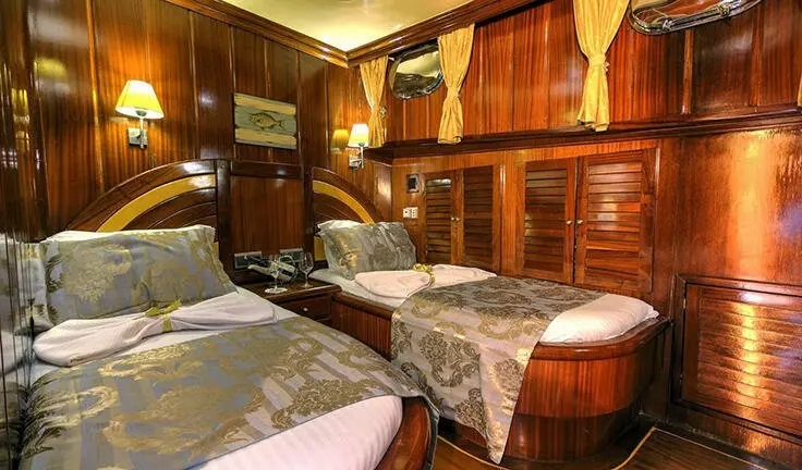 Diva Deniz yacht cabin with neatly made twin beds and wooden cabinetry