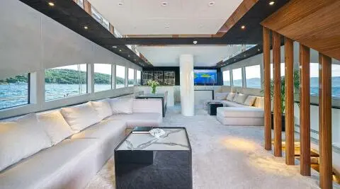 Spacious lounge with light-colored sofas and a central coffee table in a yacht interior