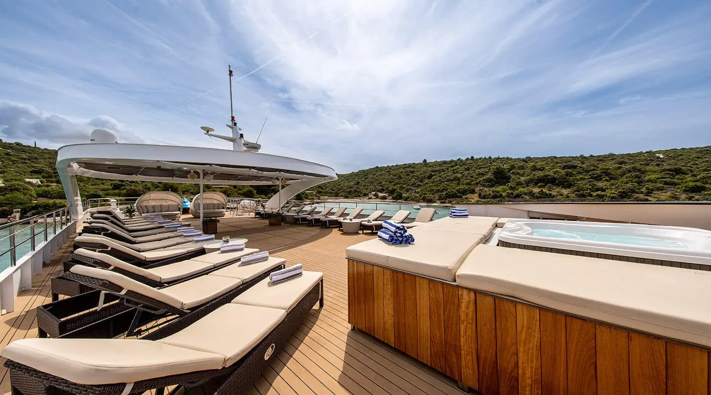 On deck of Karizma yacht, sun loungers and polished wood railings under clear sky