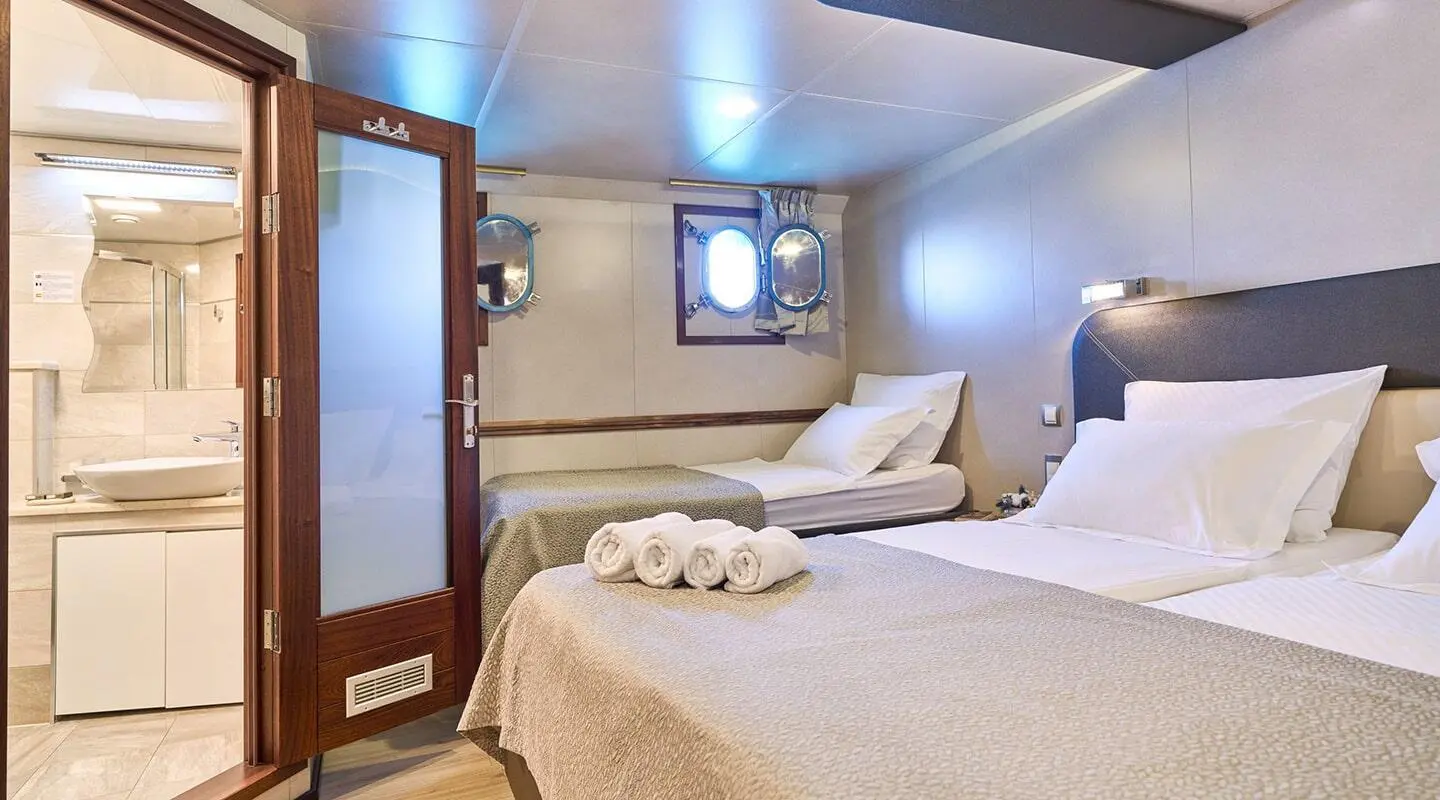 Casablanca yacht cabin with two white beds and porthole window