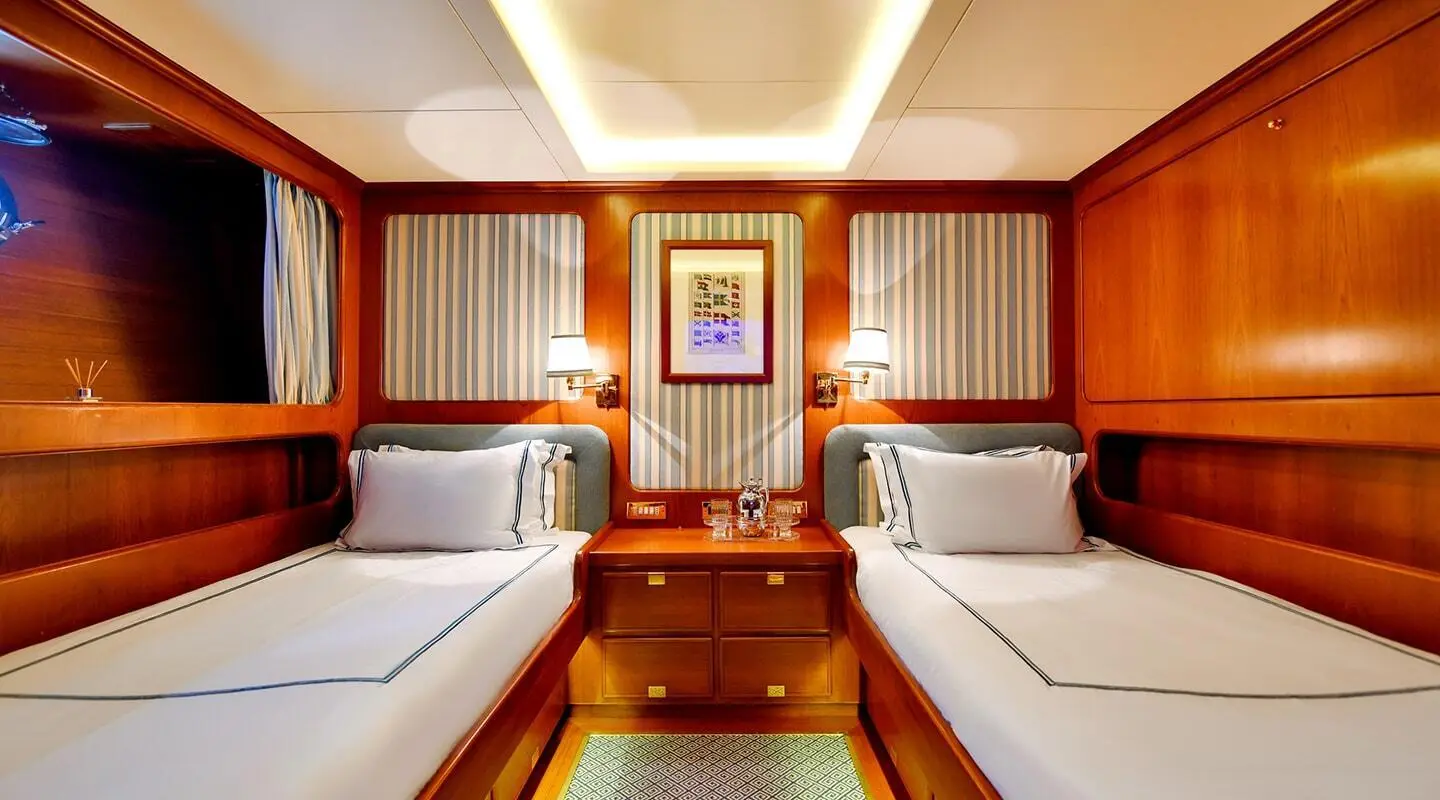 Tamarita cabin interior aboard yacht with twin beds, wood paneling, and framed art