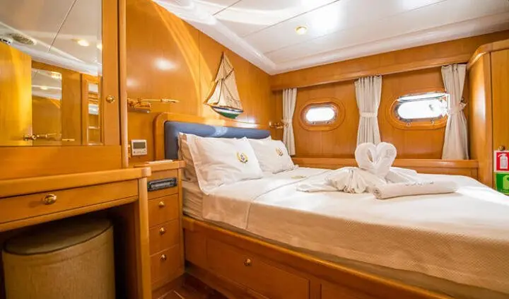 Master cabin with king bed, wood paneling, ensuite door, and warm lighting