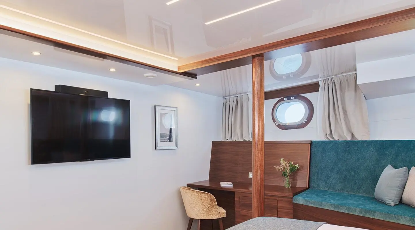 Corsario luxury gulet interior with wooden panels, seating, television screen, and porthole window