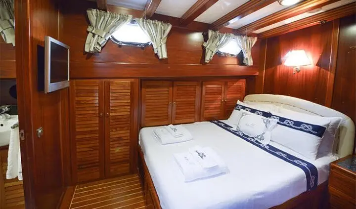 Master cabin with two beds, wooden panels, white linens and built-in storage