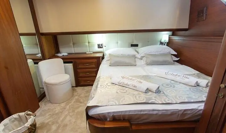 Dolce Vita yacht cabin with king bed, wood accents, and bedside lamps