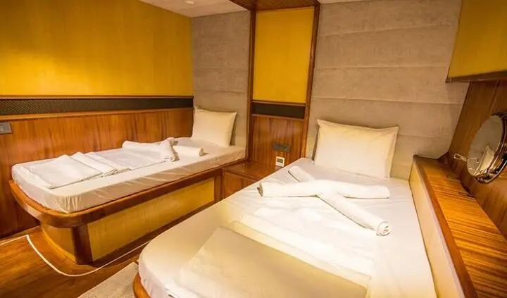 Nevra Queen cabin with two single beds, wood accents, beige bedding