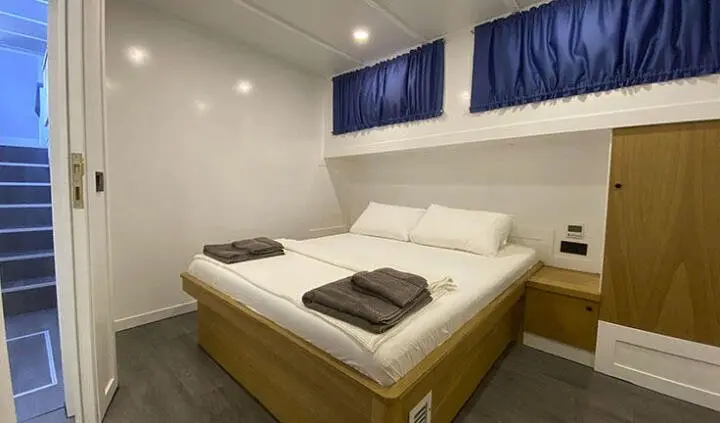 Bright cabin with two twin beds, white bedding, and blue curtains