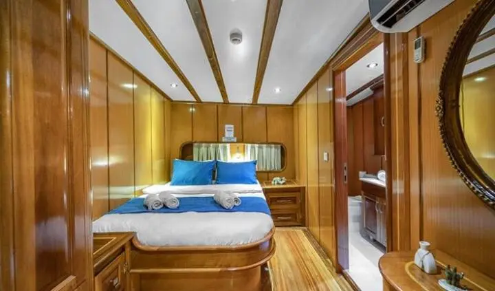 Master cabin with two blue tufted beds, wooden cabinetry and ensuite