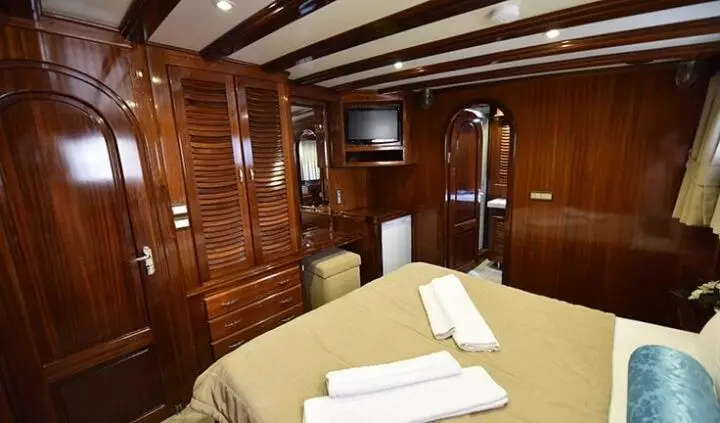 Master cabin with king bed, wood paneling, and neatly folded towels
