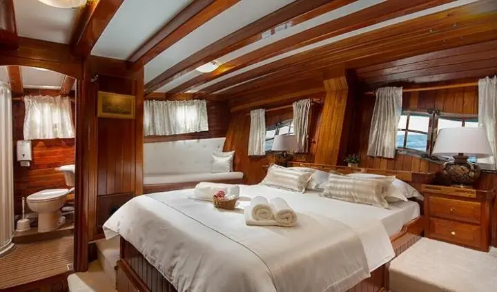 Master cabin with two single beds, wood paneling, and porthole windows