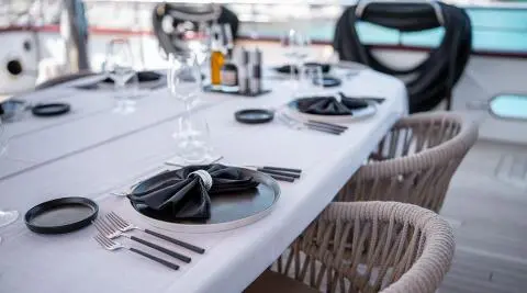 Nocturno yacht dining on deck with elegant table setting and black napkin centerpiece