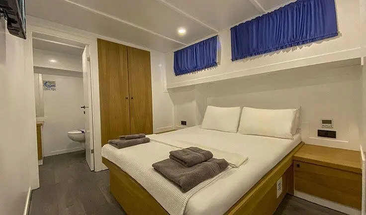 Maske 5 master cabin with king bed, white bedding, wooden accents, blue window valances