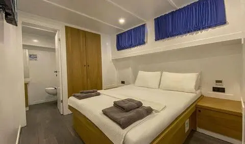 Maske 5 master cabin with king bed, white bedding, wooden accents, blue window valances