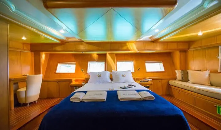 Master cabin with king bed, white linens, wooden walls, ambient lighting