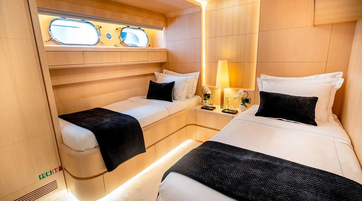 Interior of Pareaki II yacht with twin beds and warm lighting