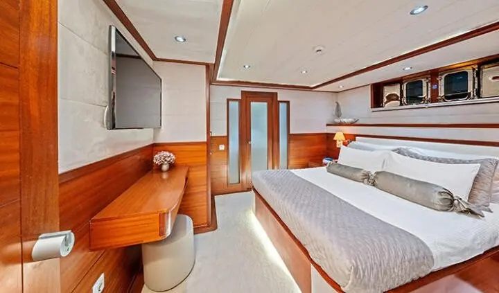 Master cabin with king bed, beige upholstery, wood cabinetry, and ensuite