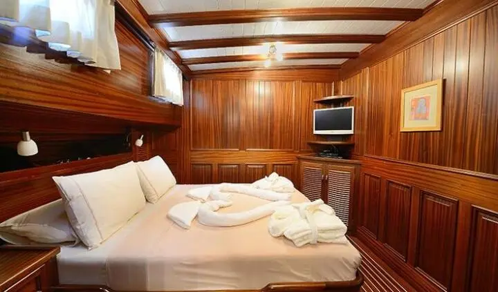 Zephyria II cabin with double bed, wooden paneling, towels folded on bed