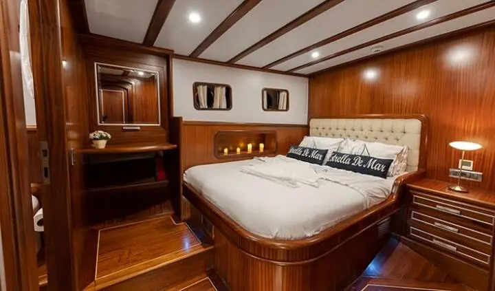 Estrella De Mar cabin with two-berth wooden bed and porthole window