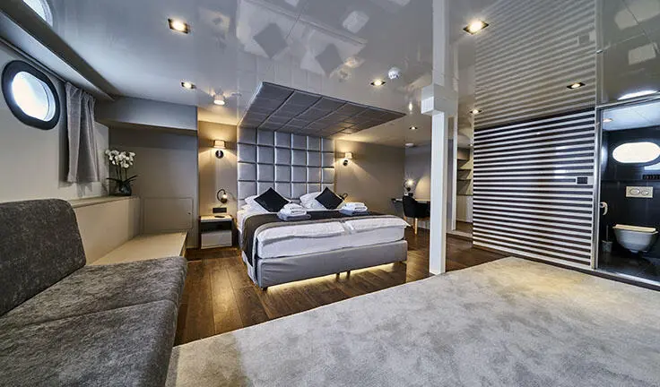 Master cabin with king bed, dark wood accents, ensuite visible