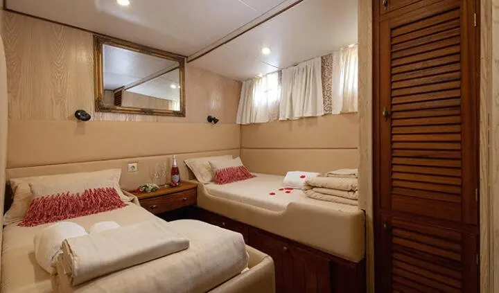 Twin cabin aboard Aborda: neatly made beds with windows and storage