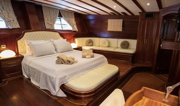 Master cabin with king bed, white linens, wooden walls, and porthole windows