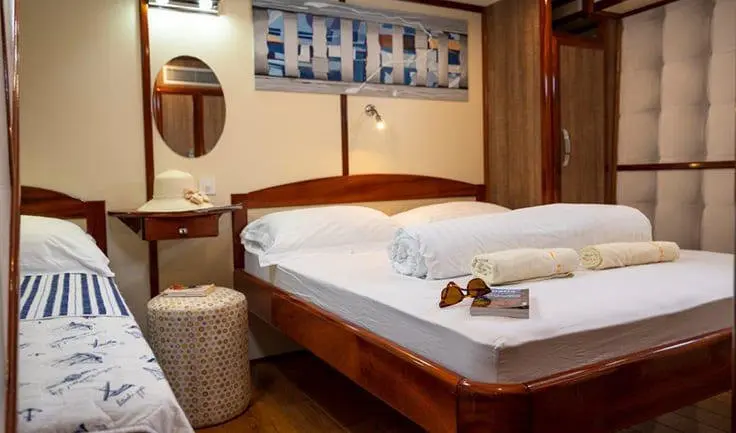 Interior of Mendula yacht cabin with bed, towels, and wooden decor.