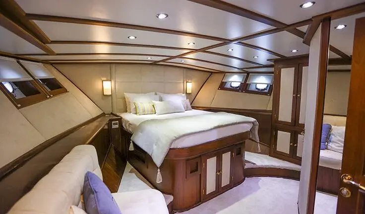 Gazella yacht master cabin with king bed, wood cabinetry, and en-suite hint
