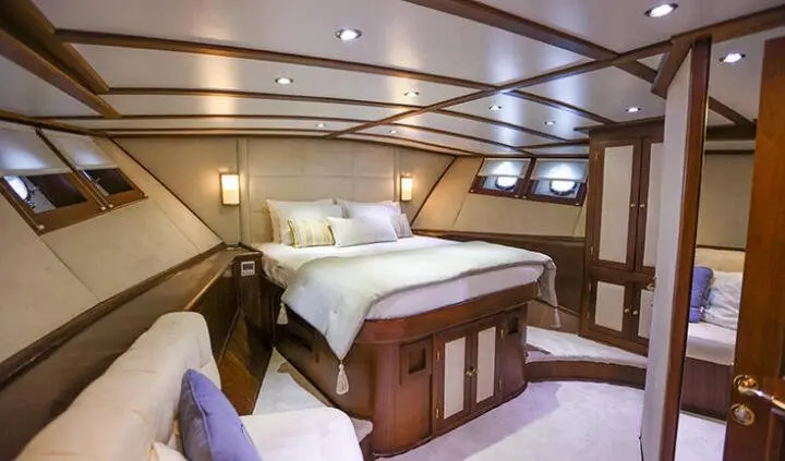 Gazella yacht master cabin with king bed, wood cabinetry, and en-suite hint