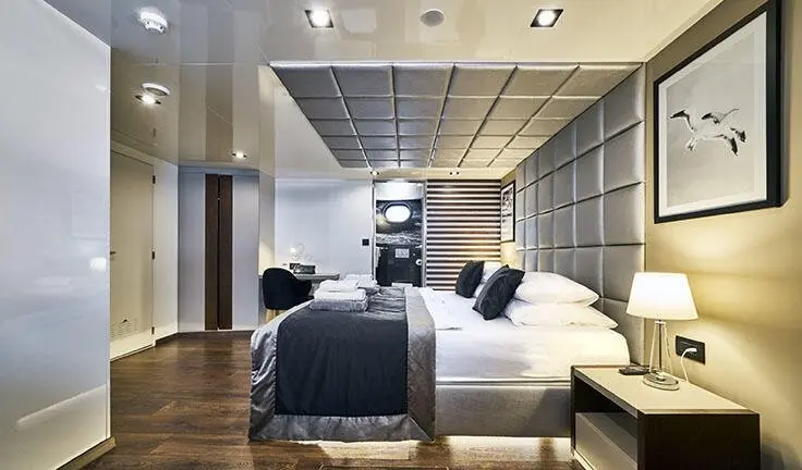 Master cabin with king bed, dark bedding, gray walls, built-in wood storage