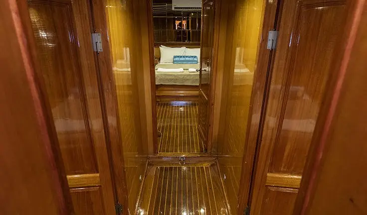 Master cabin with king bed, wood paneling, and ensuite doorway on a yacht
