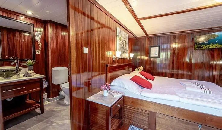 Cesarica yacht cabin with double bed and king-sized pillows, wooden cabinetry