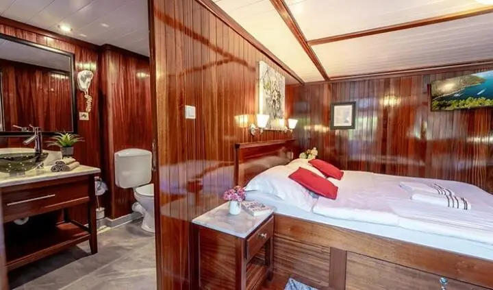 Cesarica yacht cabin with double bed and king-sized pillows, wooden cabinetry
