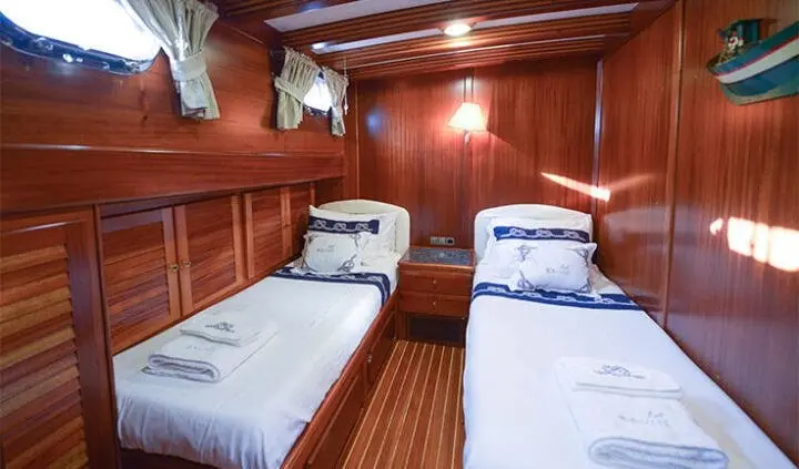 Twin cabin aboard Ros Mare yacht with two single beds and wooden paneling