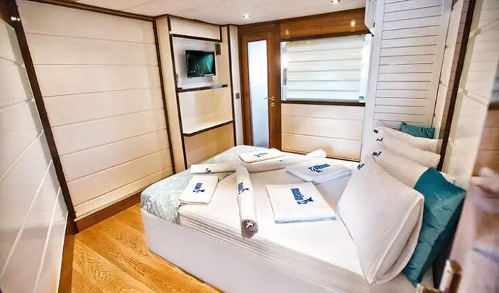 Maske 2 cabin ensuite: cozy bed with white linens and wooden accents