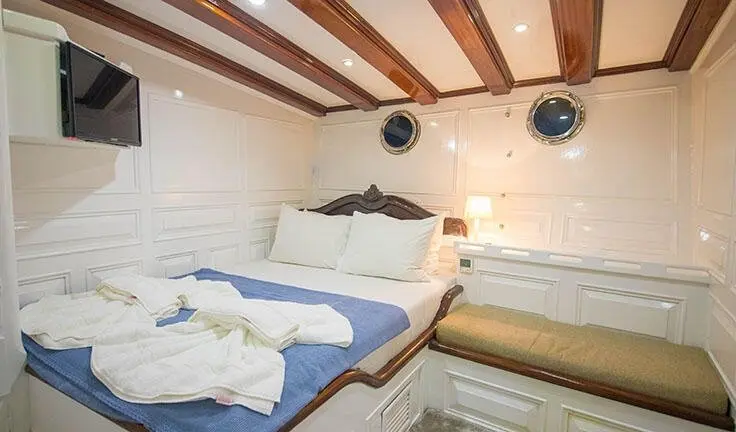 Grande Mare yacht cabin with king bed, white linens, wood ceiling beams