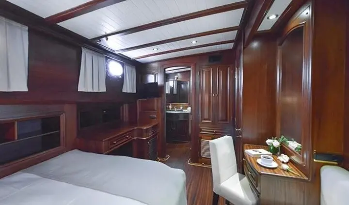 Master cabin with king bed, wood paneling, and ensuite area on yacht Lady Christa