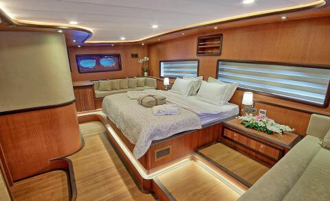 Luxurious wood-paneled yacht cabin with a large bed and cushions