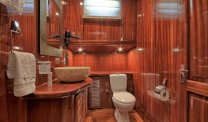 Lycian Queen cabin ensuite aboard a polished wood yacht interior with toilet and sink