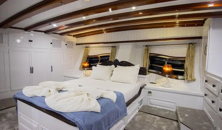 Master cabin with king bed, white linens, wood accents, and built-in nightstands