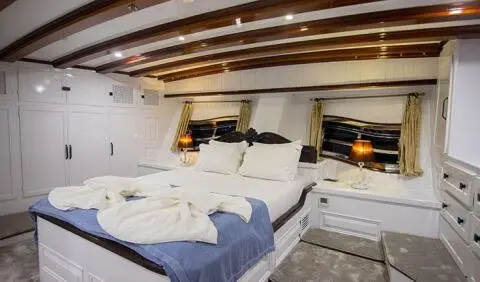 Master cabin with king bed, white linens, wood accents, and built-in nightstands