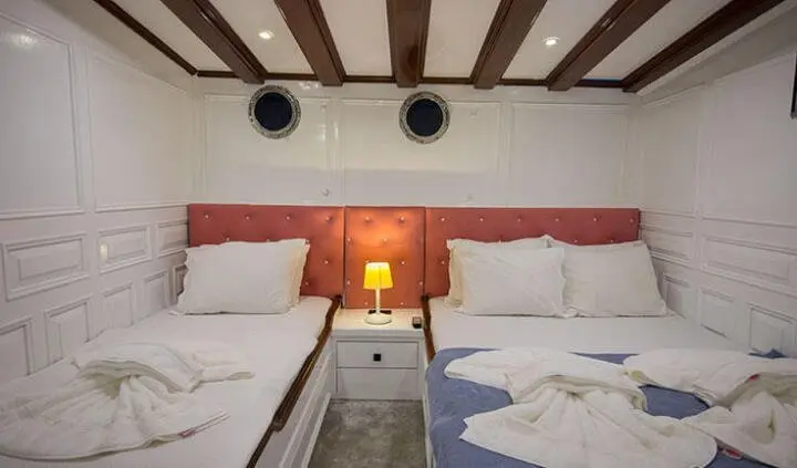 Two bunk beds in a compact cabin with white bedding and wood beams