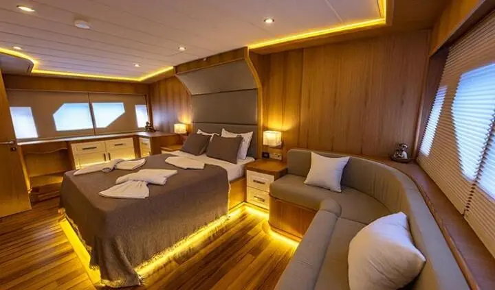 Master cabin with king bed, ensuite, warm lighting, wood tones, and seating