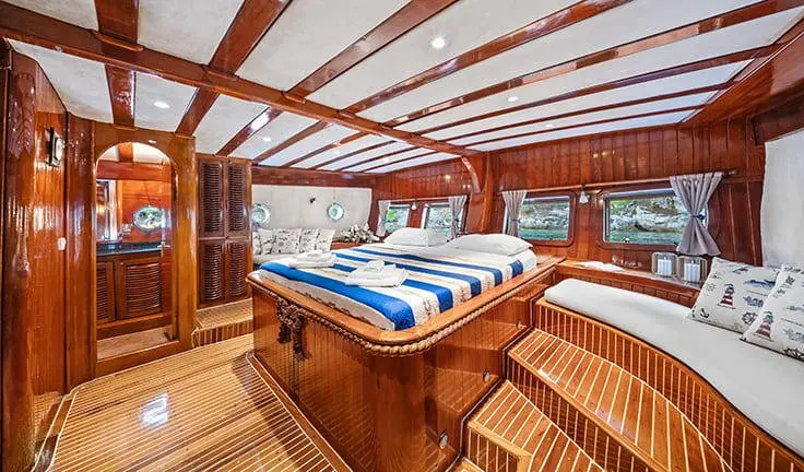 Master cabin with king bed, ensuite, polished wood interiors, blue linens