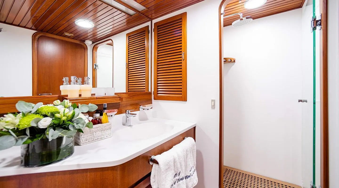 Interior yacht bathroom with wooden shelves, sink, mirror, and towels