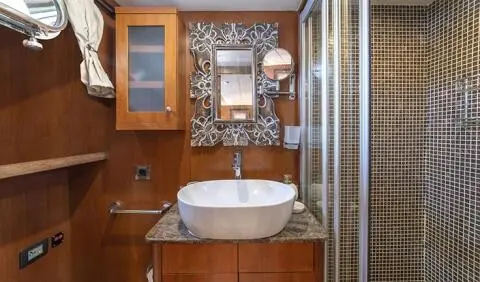 Arabella cabin ensuite bathroom with pedestal sink, mirror, wooden cabinetry